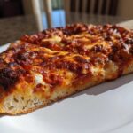 Close-up of a thick slice of cheesy pizza showing the airy crumb of the sourdough discard pizza dough crust.
