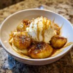 A close-up of delicious bananas foster topped with vanilla ice cream and caramel drizzle.