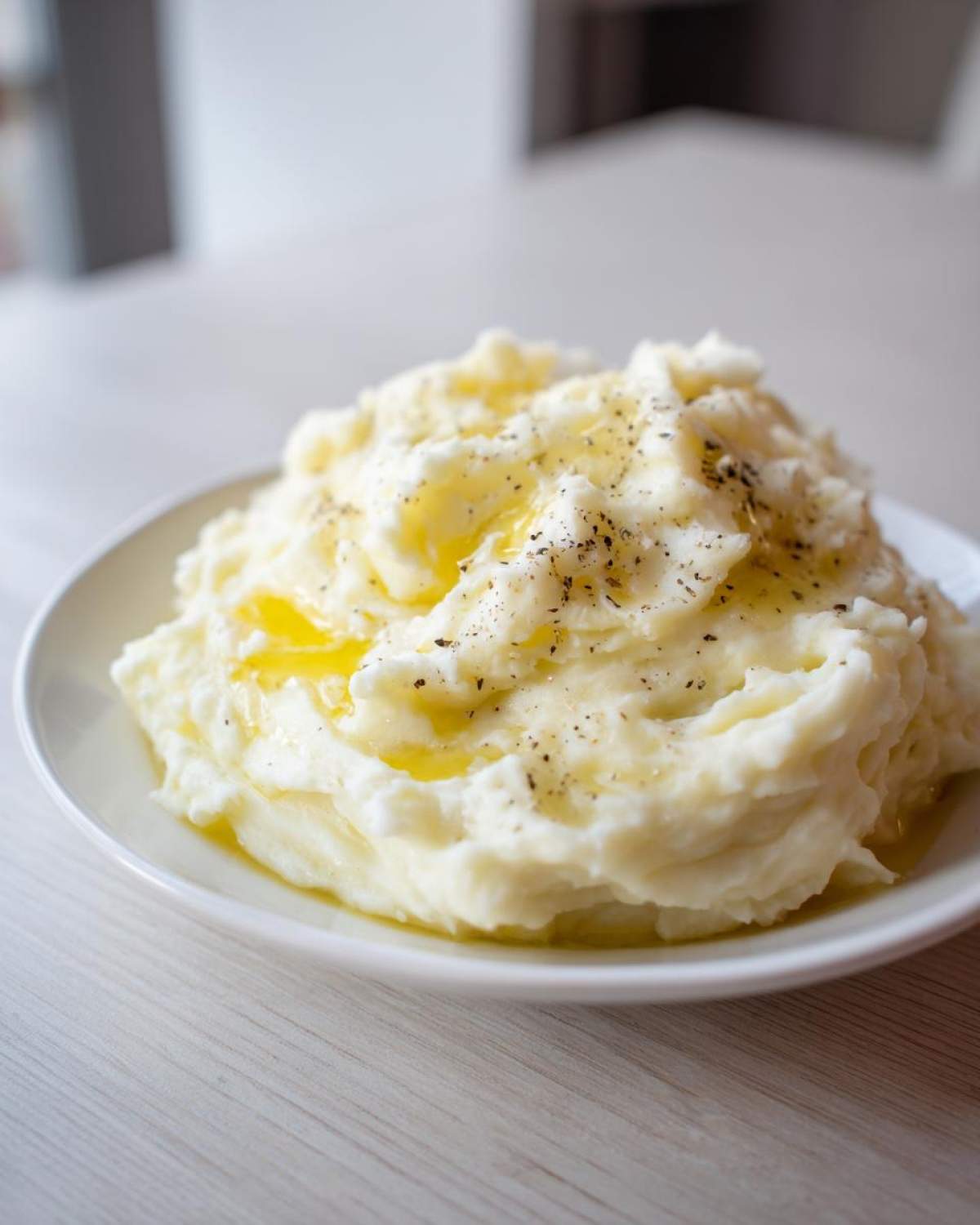 A generous serving of creamy, fluffy mashed potatoes topped with melted butter and cracked black pepper.