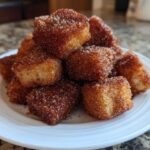 A close-up of a white plate piled high with Air Fryer Crispy Cinnamon French Toast Bites coated in cinnamon sugar.