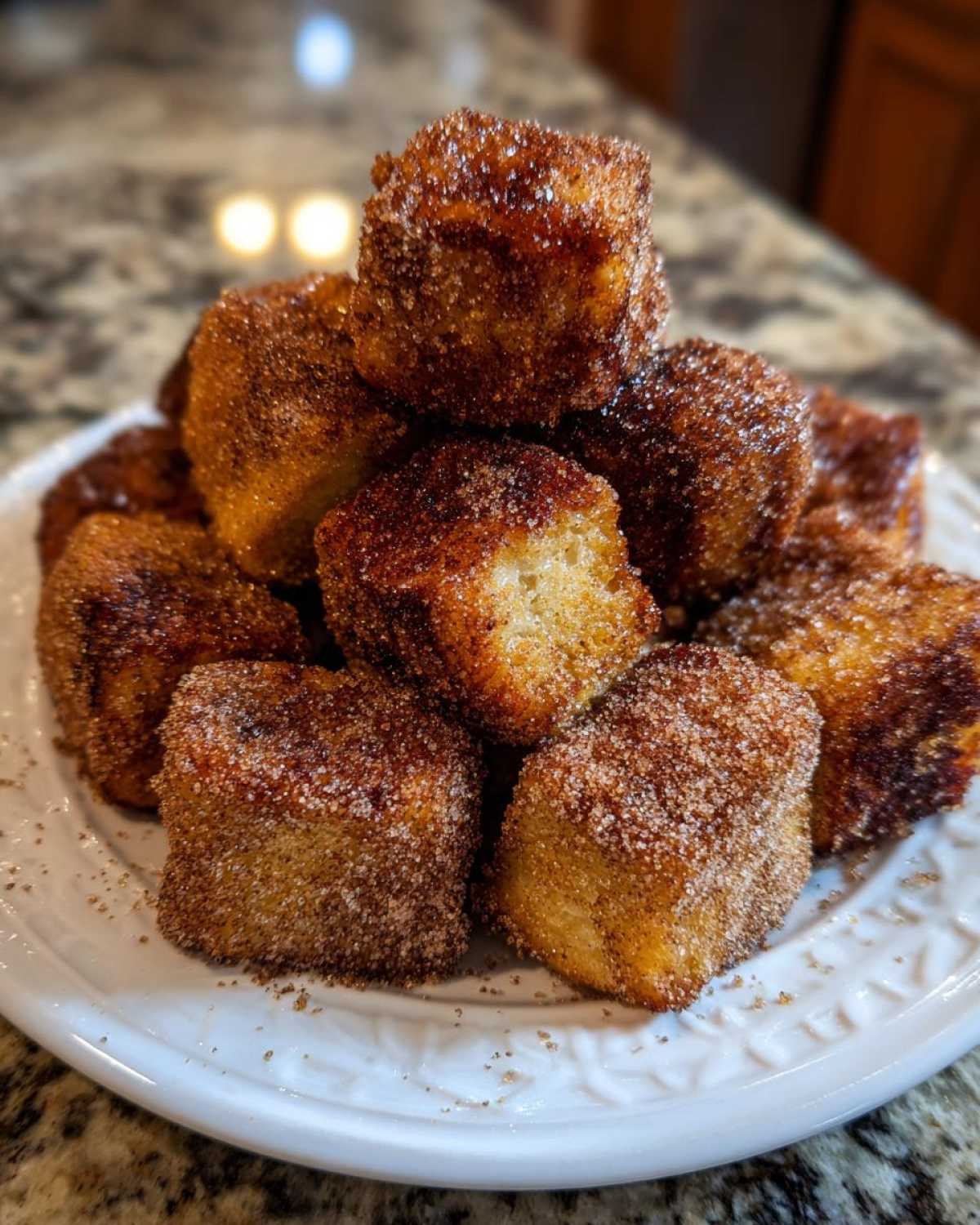A stack of golden brown Air Fryer Crispy Cinnamon French Toast Bites coated heavily in cinnamon sugar.