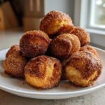 A mound of golden brown Air Fryer Crispy Cinnamon Sugar Pretzel Bites piled high on a white plate.