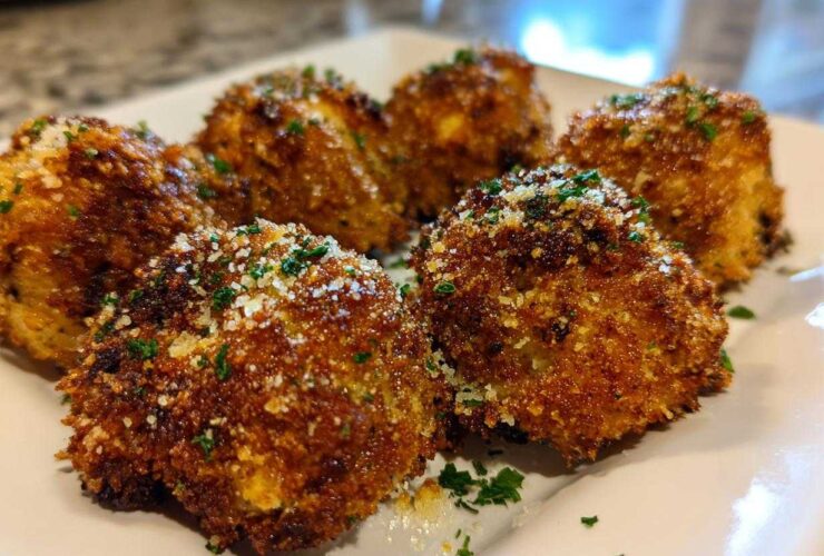 Close-up of golden brown, crispy Air Fryer Crispy Garlic Parmesan Mushrooms sprinkled with grated cheese and parsley.