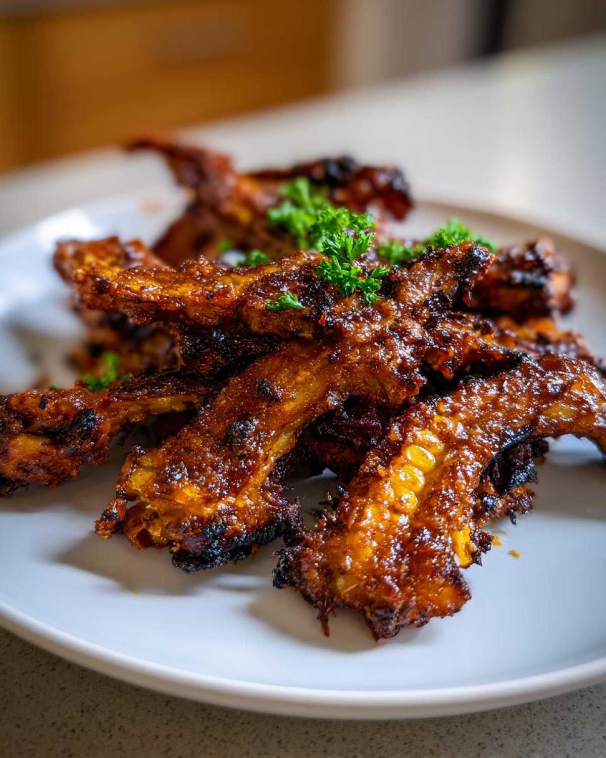 A pile of beautifully caramelized Air Fryer Crispy Parmesan Garlic Corn Ribs garnished with fresh parsley on a white plate.