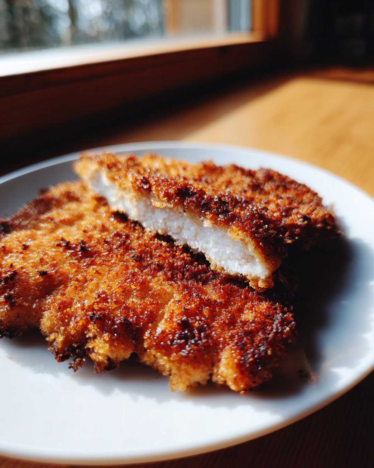 Close-up of Air Fryer Crispy Parmesan Pork Schnitzel, showing the golden, crunchy exterior and white interior.