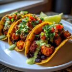 Three Air Fryer Crispy Sweet Potato Tacos filled with black beans, topped with salsa and green sauce.