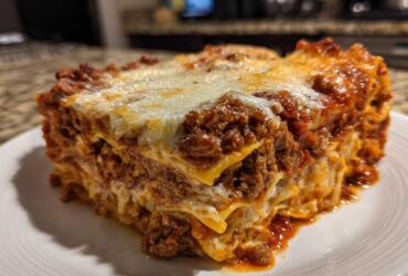 A thick, layered slice of baked lasagna with rich meat sauce and melted cheese topping.