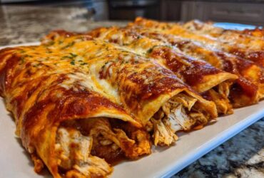 Close-up of freshly baked chicken enchiladas covered in red sauce and melted cheese, revealing shredded chicken filling.