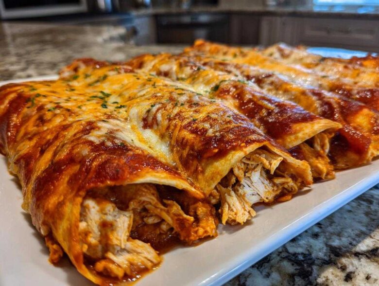 Close-up of freshly baked chicken enchiladas covered in red sauce and melted cheese, revealing shredded chicken filling.