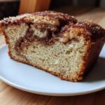 Close-up of a moist slice of Amish Cinnamon Bread showing a rich cinnamon swirl and sugary top.