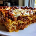 A thick, layered slice of Beef Lasagna with Ricotta and Mozzarella showing rich meat sauce and browned cheese topping.