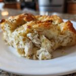 A close-up view of a serving of Casserole Crescent Rolls filled with shredded chicken and creamy sauce on a white plate.