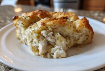 A close-up view of a serving of Casserole Crescent Rolls filled with shredded chicken and creamy sauce on a white plate.