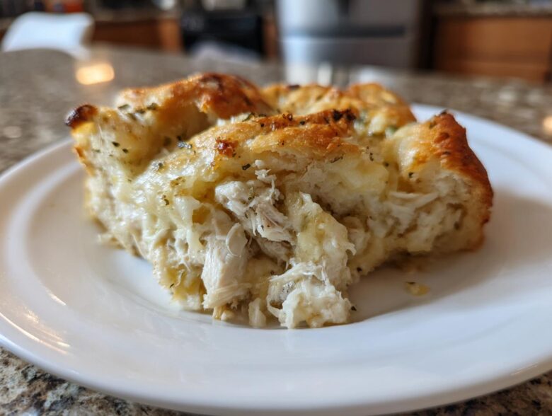 A close-up view of a serving of Casserole Crescent Rolls filled with shredded chicken and creamy sauce on a white plate.