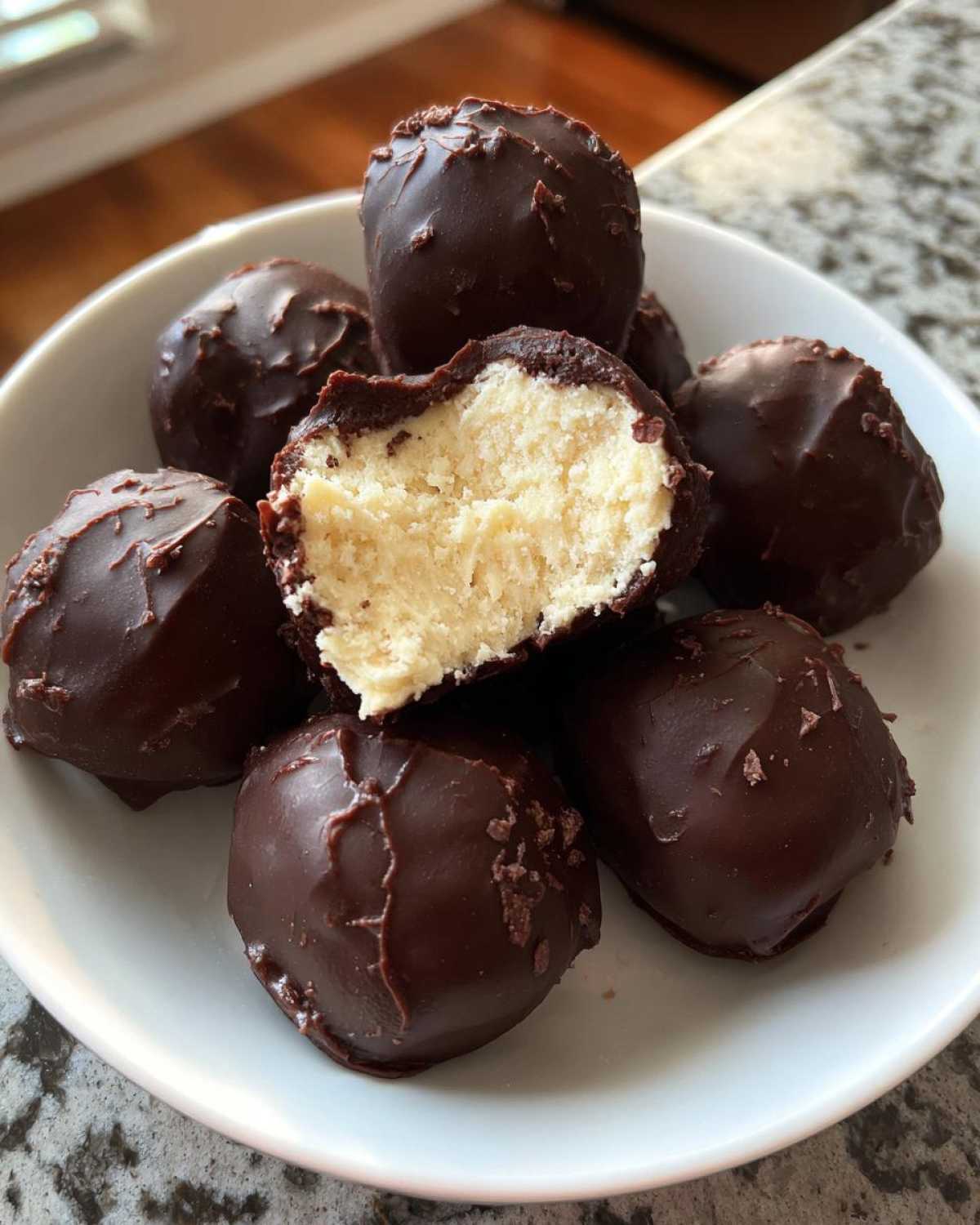 A pile of rich Chocolate Chip Cookie Dough Truffles NoBake, one cut open to show the creamy, light-colored center.