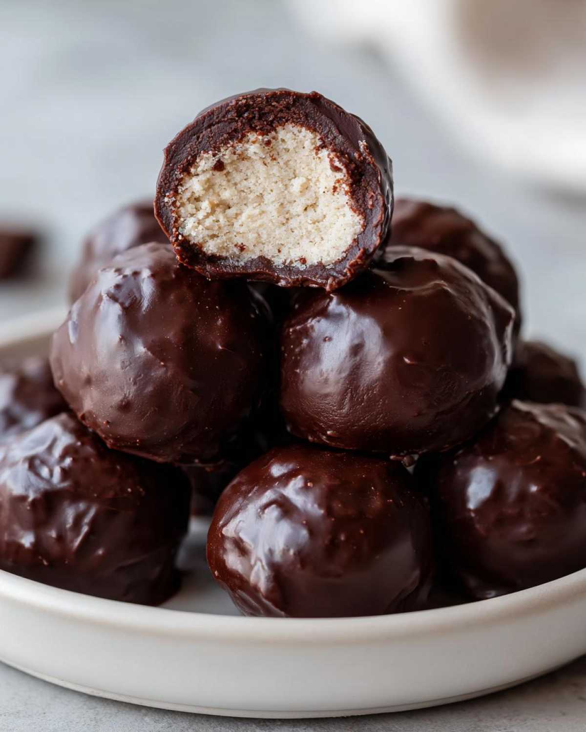Stack of rich Chocolate Chip Cookie Dough Truffles NoBake, one cut in half showing the light-colored dough center.