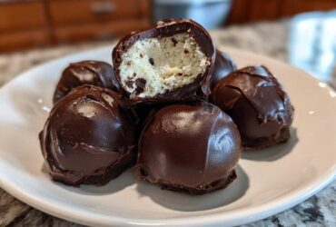 A stack of rich Chocolate Chip Cookie Dough Truffles NoBake, one cut open showing the doughy center.