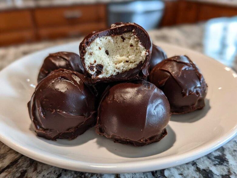 A stack of rich Chocolate Chip Cookie Dough Truffles NoBake, one cut open showing the doughy center.
