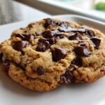 Close-up of a gooey, freshly baked Chocolate Chip Cookie For One with melted chocolate chunks on a white plate.