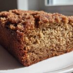Close-up of a moist slice of Cinnamon Crumb Banana Bread showing the dense crumb and thick, sugary cinnamon topping.