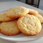 A stack of freshly baked Classic Vanilla Sugar Cookies, coated generously with sparkling granulated sugar, resting on a white plate.