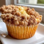 A close-up of a golden baked Coffee Cake Muffin topped generously with cinnamon sugar crumble.