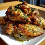 Close-up of crispy chicken wings generously coated in Copycat Garlic Parmesan Wing Sauce and topped with fresh parsley.