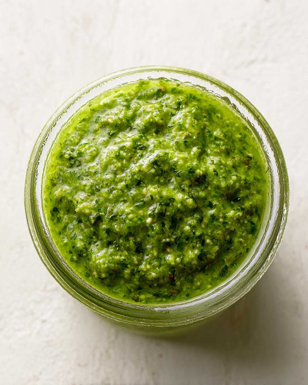 Overhead view of thick, bright green Copycat Green Goddess Ranch Dressing filling a small glass jar.
