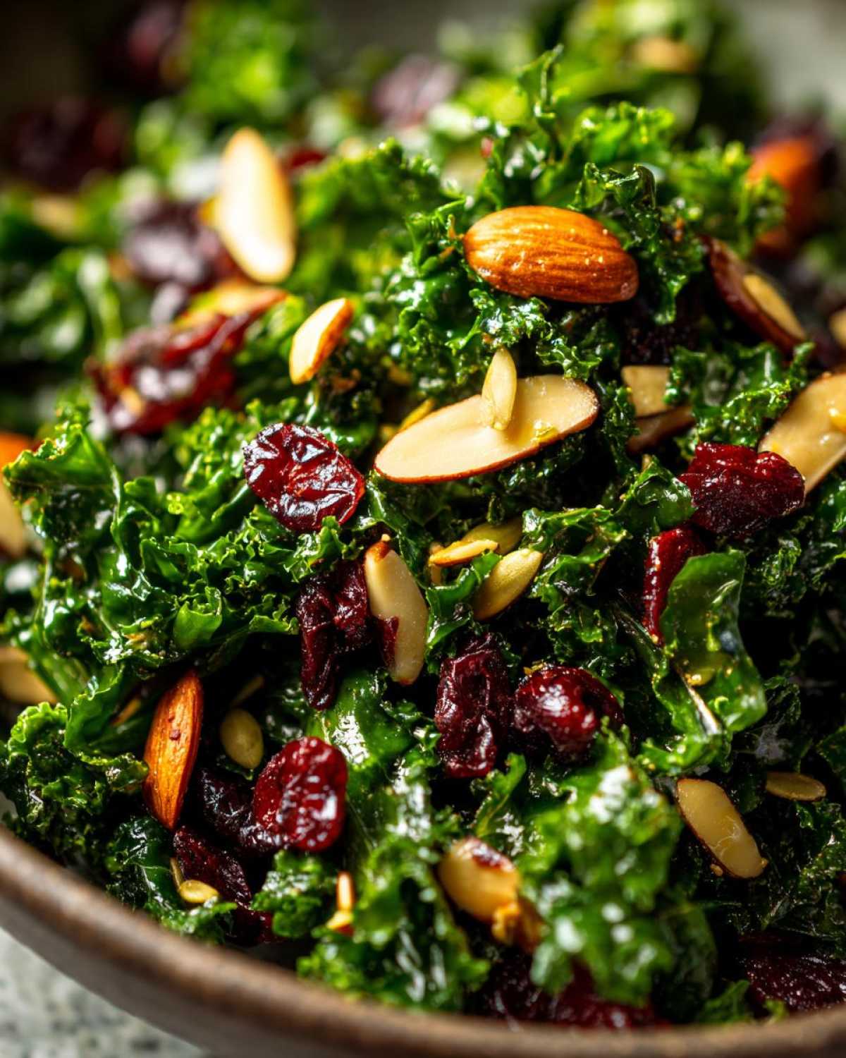 Close-up of vibrant green kale tossed with sliced almonds and dried cranberries in a Copycat Kale Crunch Salad.