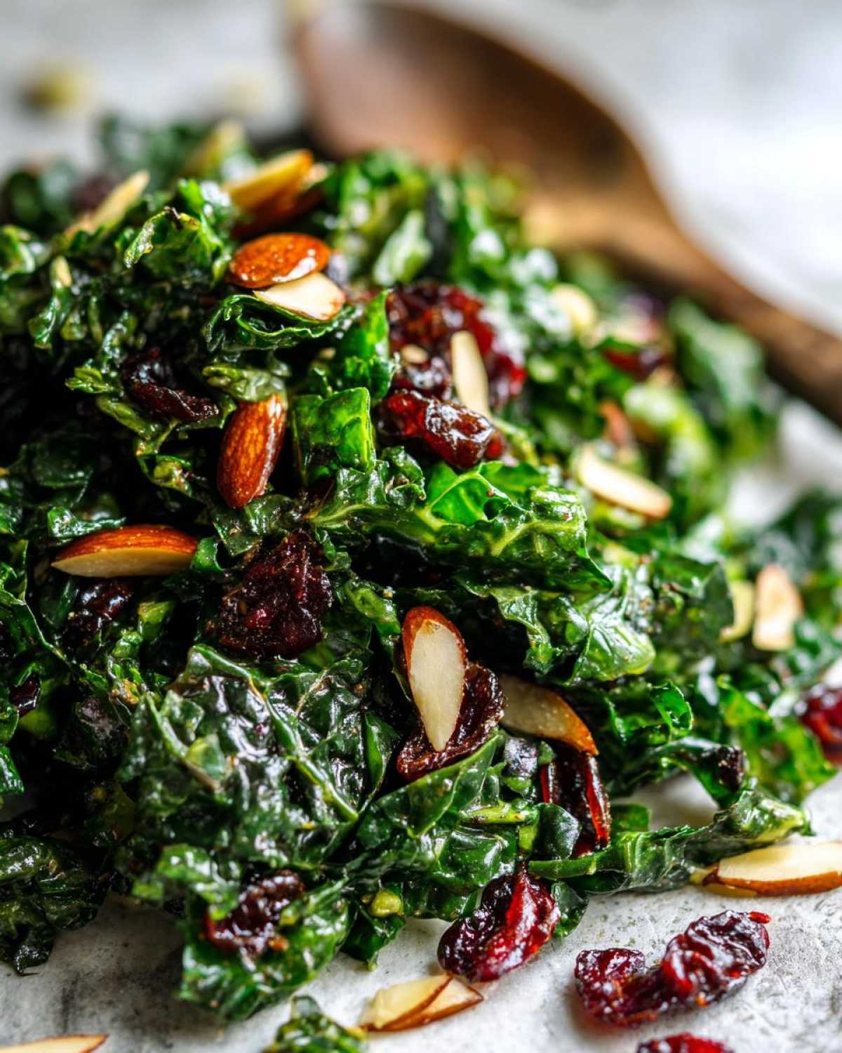 Close-up of vibrant green kale tossed with slivered almonds and dried cranberries in a Copycat Kale Crunch Salad.