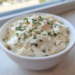 A close-up of thick, creamy Copycat Pizza Garlic Parmesan Dip Sauce garnished with fresh parsley in a small white bowl.