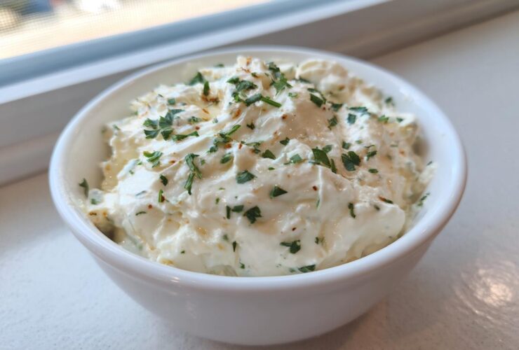 A close-up of thick, creamy Copycat Pizza Garlic Parmesan Dip Sauce garnished with fresh parsley in a small white bowl.