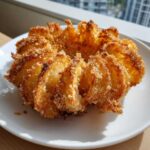 A perfectly cooked, golden brown, crispy mini blooming onion served on a white plate.