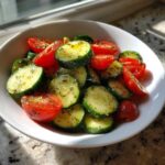 Close-up of a vibrant Cucumber Tomato Salad Low Carb, featuring sliced cucumbers and halved cherry tomatoes tossed in oil and herbs.
