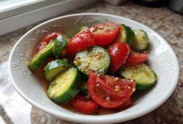 Close-up of a fresh Cucumber Tomato Salad Low Carb, featuring sliced cucumbers and cherry tomatoes tossed in a light vinaigrette.