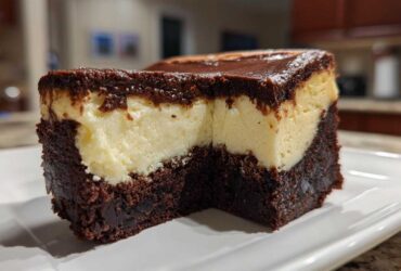 Close-up of a rich slice of Decadent Brownie Bottom Cheesecake showing the thick brownie base and creamy cheesecake layer.
