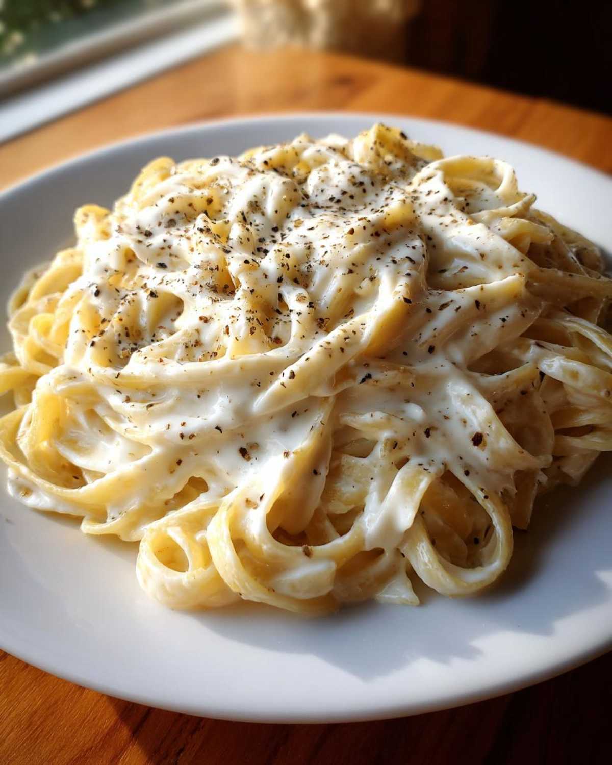 Close-up of fettuccine pasta generously coated in creamy Easy Cottage Cheese Alfredo Sauce and sprinkled with black pepper.