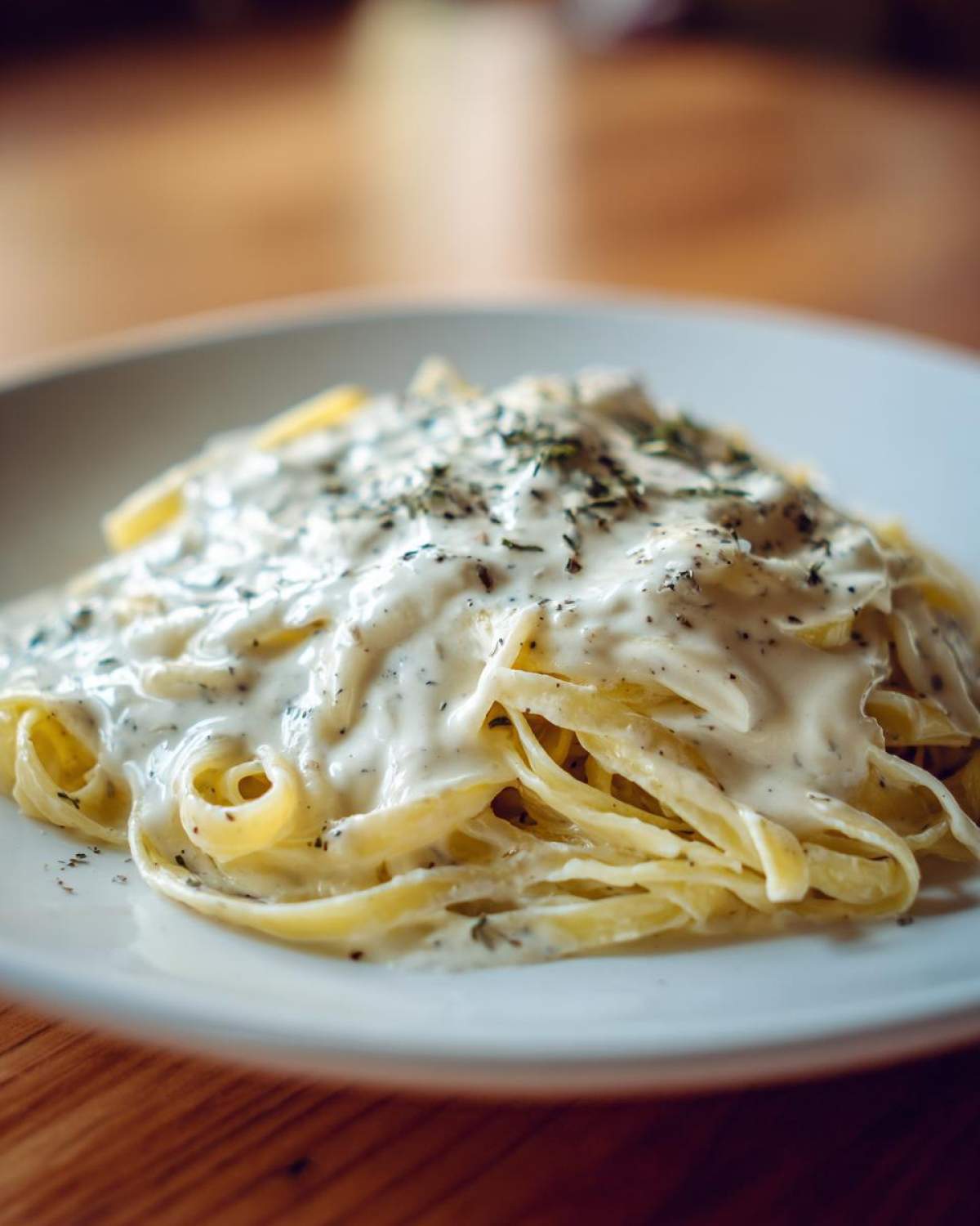 Close-up of fettuccine pasta generously coated in creamy Easy Cottage Cheese Alfredo Sauce and topped with herbs.