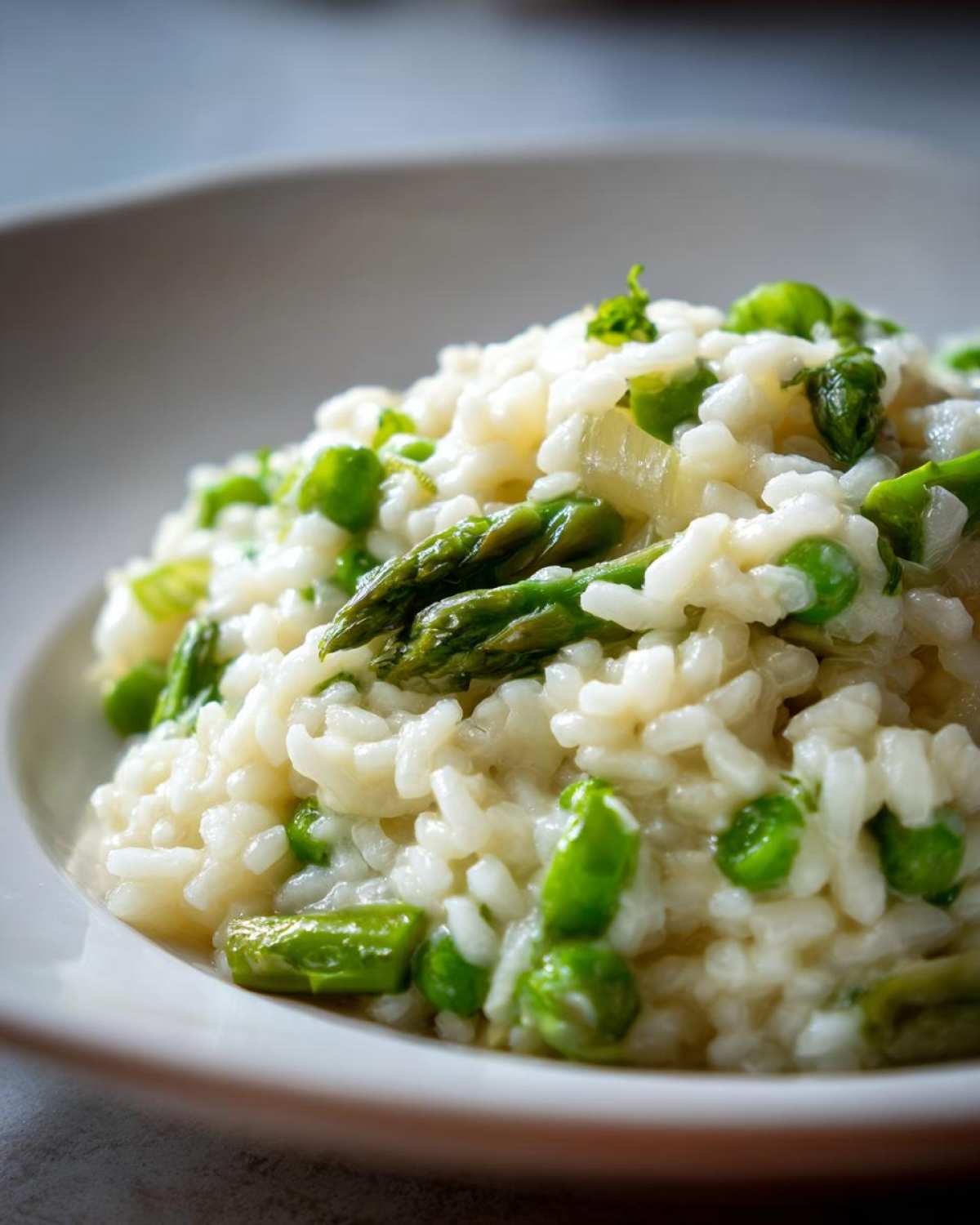 A close-up shot of creamy white rice mixed with bright green asparagus tips and peas in Easy Creamy Asparagus Risotto.