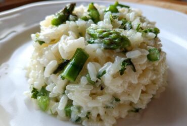 Close-up of a perfectly portioned mound of Easy Creamy Asparagus Risotto with bright green asparagus pieces.