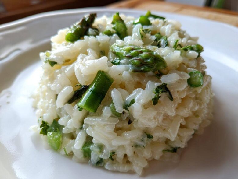Close-up of a perfectly portioned mound of Easy Creamy Asparagus Risotto with bright green asparagus pieces.