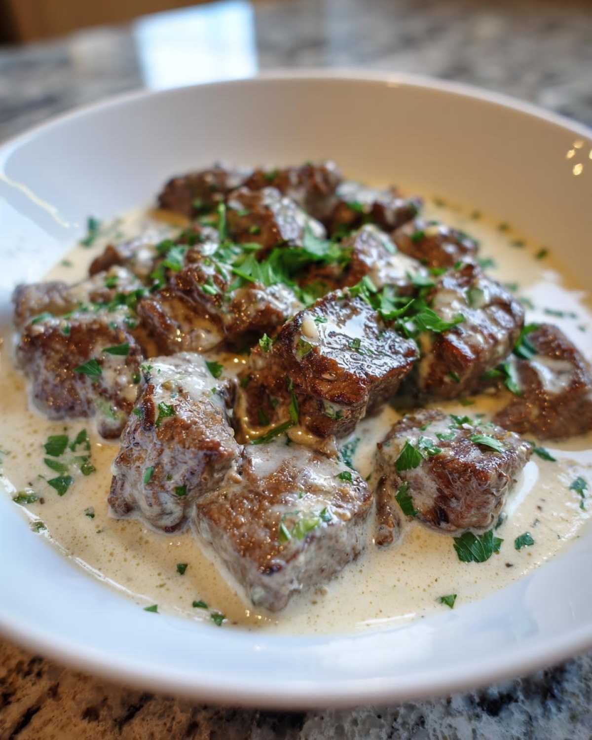 Close-up of Easy One-Pan Creamy Garlic Steak Bites coated in a rich, white garlic sauce and topped with fresh parsley.
