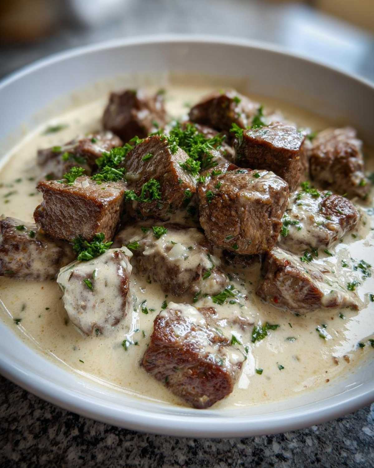 Close-up of juicy steak bites coated in a creamy garlic sauce and garnished with parsley, showcasing Easy One-Pan Creamy Garlic Steak Bites.