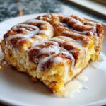 Close-up of a square serving of Easy Sheet Pan Cinnamon Roll Pancake Bake drizzled with white icing.