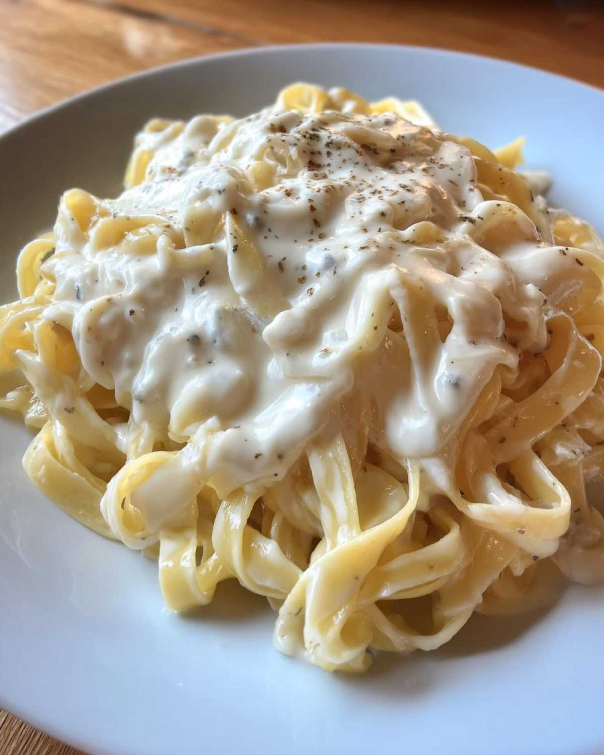 Close-up of fettuccine pasta coated generously in creamy Easy Cottage Cheese Alfredo Sauce and sprinkled with pepper.