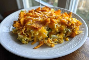 A serving of Frito Cowboy Cabbage on a white plate, topped with melted cheddar cheese and crunchy Fritos corn chips.
