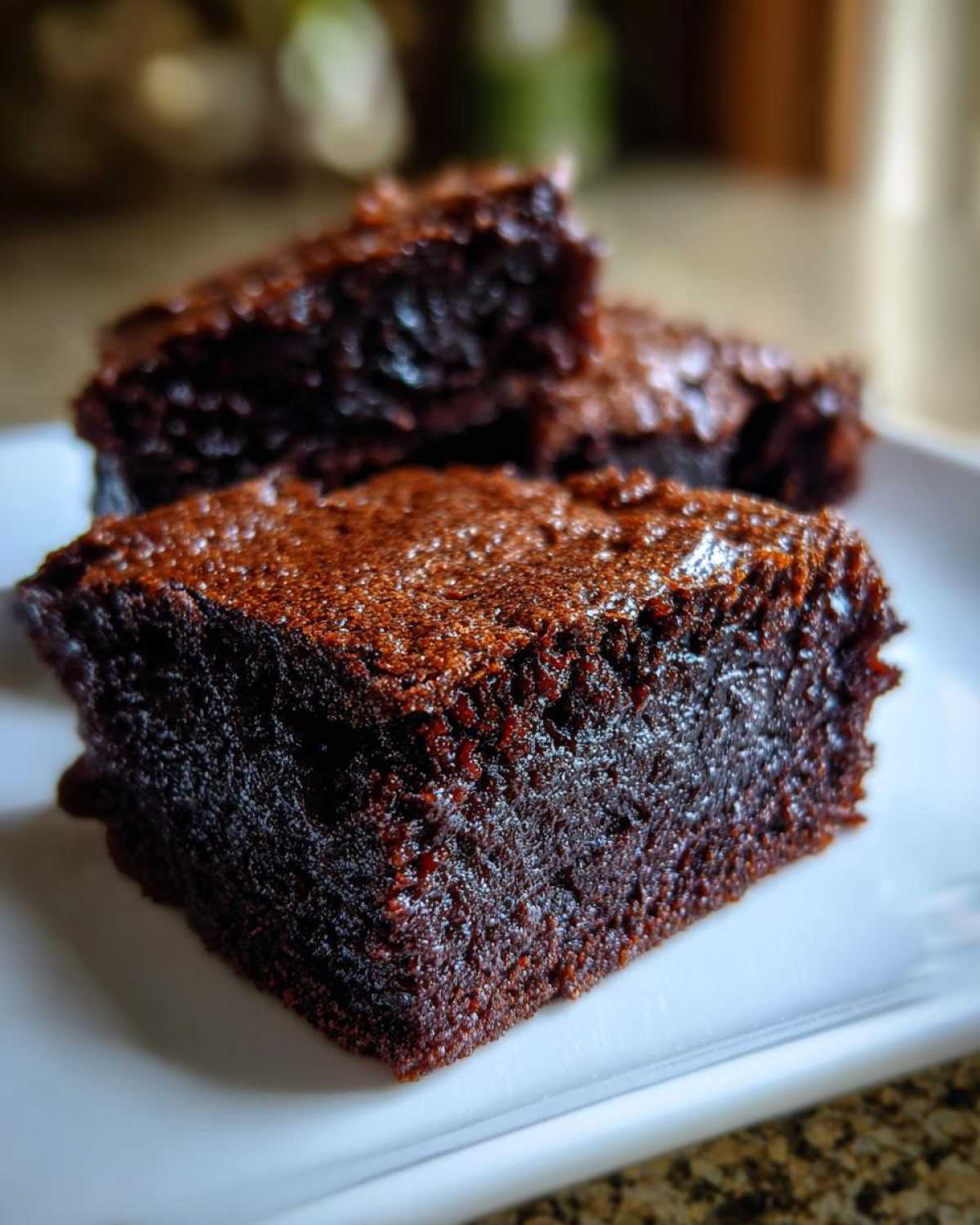 Close-up of a rich, dark, fudgy Greek Yogurt Brownies square on a white plate.