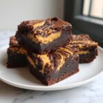 A stack of fudgy Gluten-Free Chocolate Peanut Butter Swirl Brownies on a white plate.