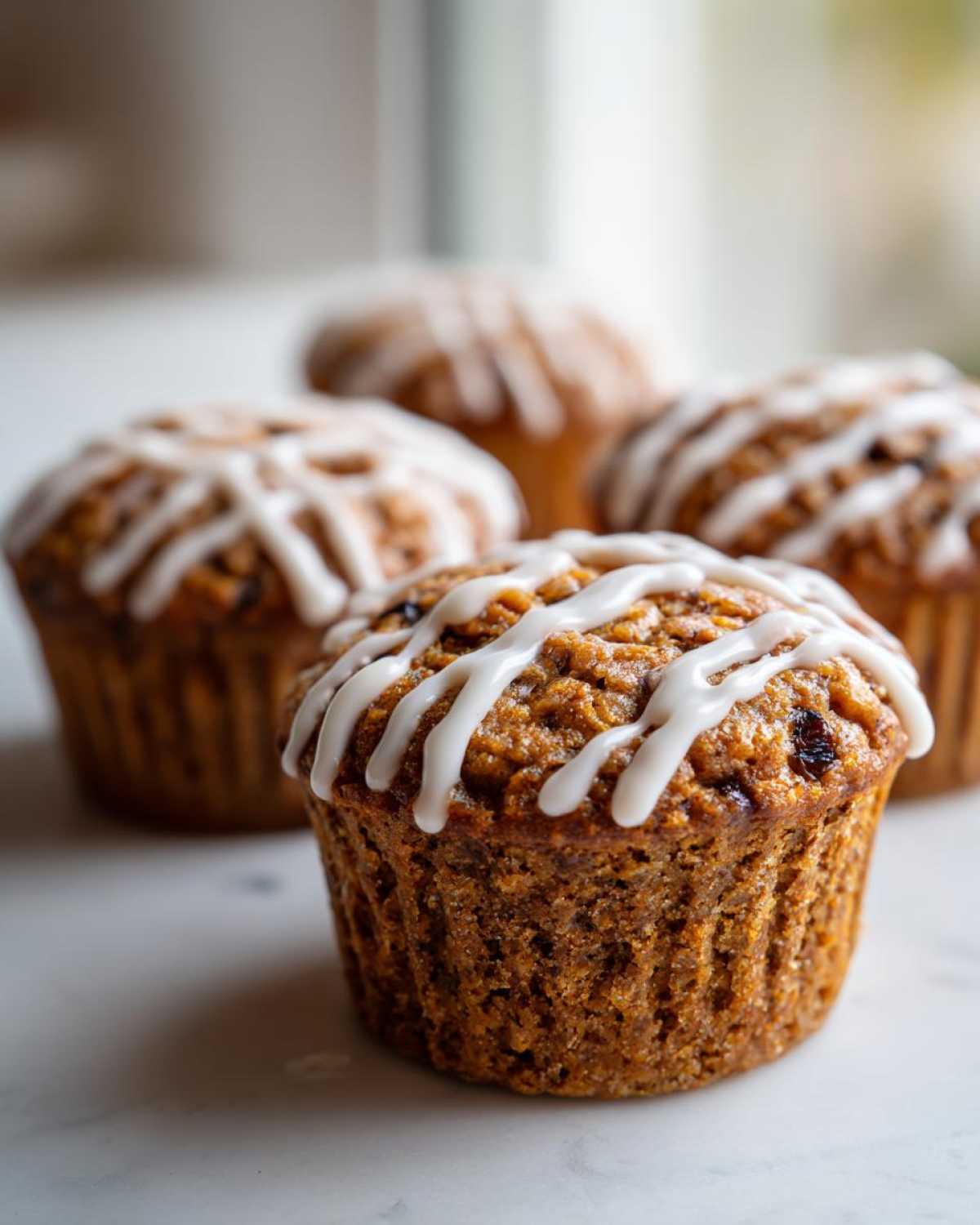 Close-up of a freshly baked Gluten-Free Hot Cross Bun Muffin topped with white icing drizzle