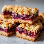 A stack of moist Gluten-Free Lemon Berry Crumble Bars showing the thick berry filling and crumbly topping.